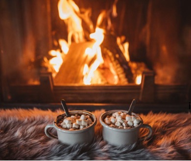 two mugs of hot chocolate in front of a fire in fireplace