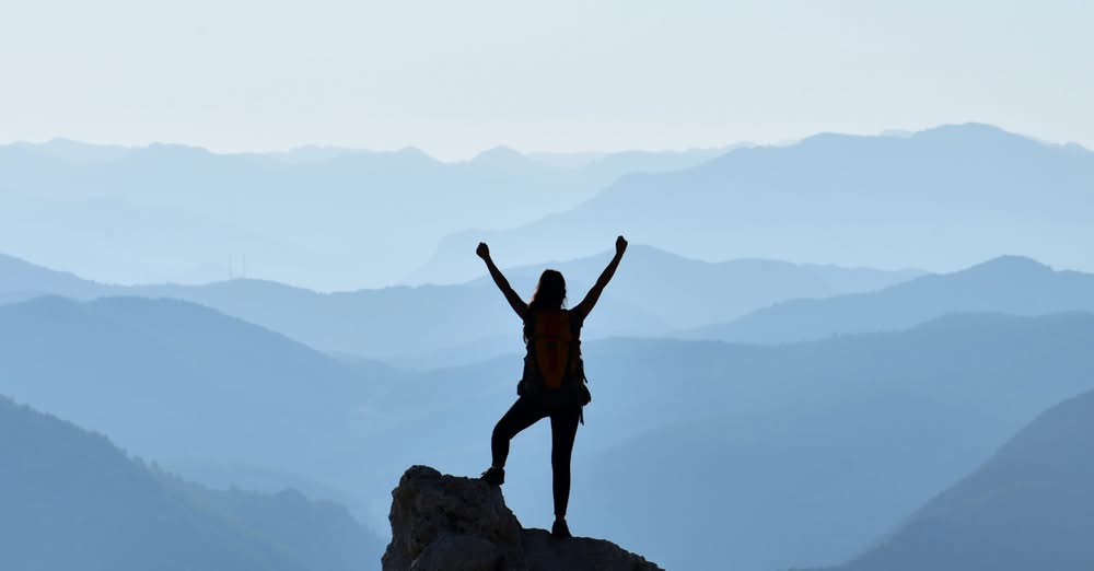 Woman who reached the top of a mountain celebrating 